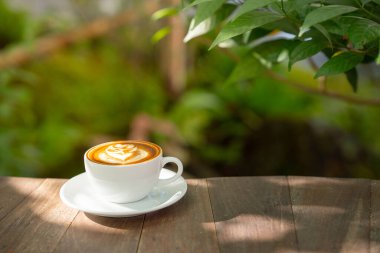 Sıcak sanat sütlü kahve. Arka plan kahve fincanı ve fasulye. Eski mutfak masasında..