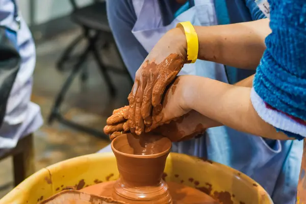 hands of a potter in a clay jar