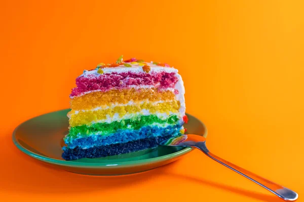 rainbow cake with cream on a colored background