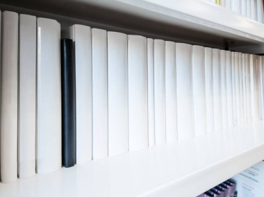 A white bookshelf filled with white books, featuring a small black book in the center, symbolizing knowledge, equality, and the fight against racism. clipart