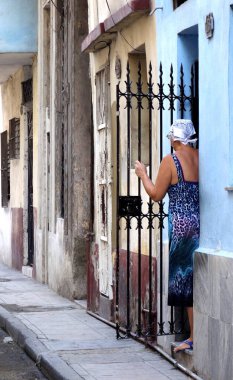Women in a blue dress watching the streets of havana with colorful buildings. High quality photo