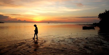 Filipinler 'in yumuşak günbatımı ve bir çocuk silueti. Su gün batımını yansıtıyor. Yüksek kalite fotoğraf