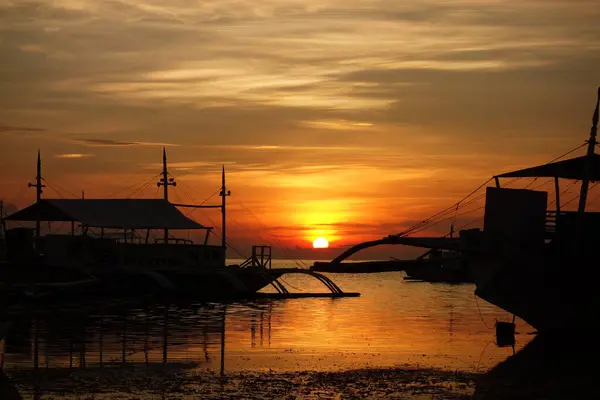 Sunset Harbor in the Philippines. Soft clouds and reflection in the water. Silhouette of a boat and jetty. High quality photo