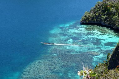 Endonezya 'nın geleneksel teknesi mercanlarla dolu büyülü ve berrak bir lagünün içinden çıkıyor. Yüksek kalite fotoğraf