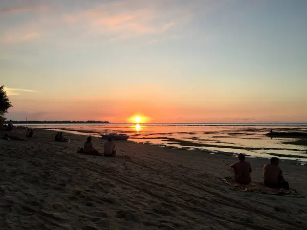 İnsanlar kumsalda kumsalda oturup Gili Air Island Endonezya 'da günbatımını seyrediyorlar. Yüksek kalite fotoğraf