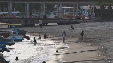 Çocukların güzel bir gün batımında sıcak suyun tadını çıkardıkları huzurlu bir sahil sahnesi.