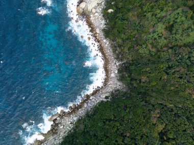 Nefes kesici hava perspektifi açık mavi okyanus dalgalarıyla kusursuz bir şekilde birleşen canlı yeşil bir kıyı şeridini gösteriyor.