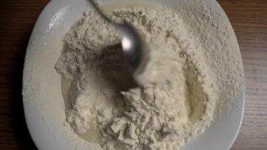 Kız bir kaşıkla unu ve suyu karıştırdı. Mangırı hazırlıyorum. Pişirme çizelgeleri