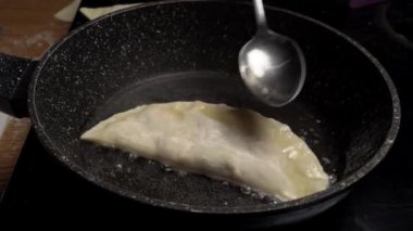 Kızartma tavasında cheburek kızartan bir kız. Sıcak bir tava. Çebuk 'u ayçiçeği yağıyla sulamak