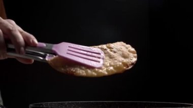 Kız pişmiş cheburekleri tabağa koyar. Pişmiş cheburekler. Kızarmış cheburekler.