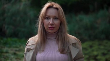 Bir kadın dikkatle kameraya bakıyor. Model üzerinde kameralar düzgün çalışıyor. Açık renkli yağmurluk giyen sarışın bir kadın. Güzel zıt arkaplan