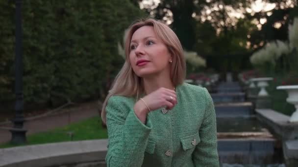 Une Femme Assise Devant Une Fontaine Blonde Costume Vert Apporte — Video