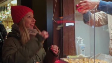 Bir kız, Köln 'ün merkezindeki bir Noel fuarında şeker alır. Satıcıya para verir ve bozuk para alır. Kırmızı şapka. Neşeli ve gülen yüz.