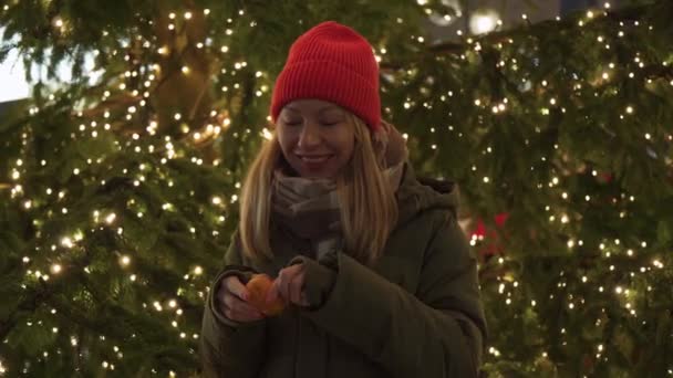 Ένα Κορίτσι Ξεφλουδίζει Ένα Μανταρίνι Κοντά Στο Χριστουγεννιάτικο Δέντρο Ένα Πλάνα Αρχείου