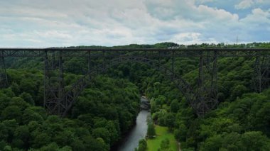 Mungstener Brucke Germanys 'in en uzun demiryolu köprüsüne doğru geniş açıyla uçuyor. Ağaçlarla ve Wupper Nehri 'nin altındaki parklarla çevrili tüm yapıyı gösteriyor. Parçalı bulutlu bir günde 4K 'da yakalandı.