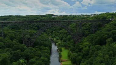 Mungstener Brucke Germanys 'in soldan sağa uçan en yüksek demiryolu köprüsünün geniş açılı görüntüsü. Yolcu treni Wupper Nehri ve aşağıdaki yeşil ağaçlarla köprüden geçer. Parçalı bulutlu bir günde 4K 'da yakalandı.