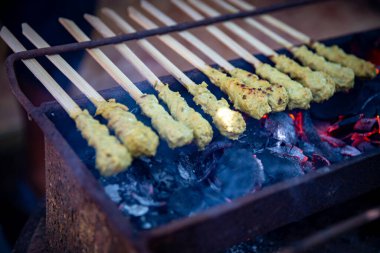 Satay hindistan cevizi parçalarının üstünde ızgarada pişiyor.