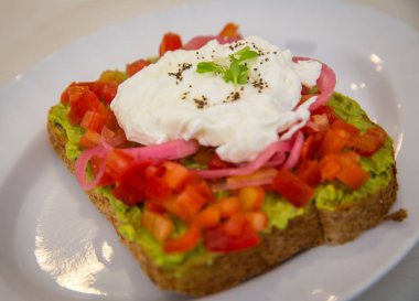 Yumurtalı, domatesli ve soğanlı avokado tostu.