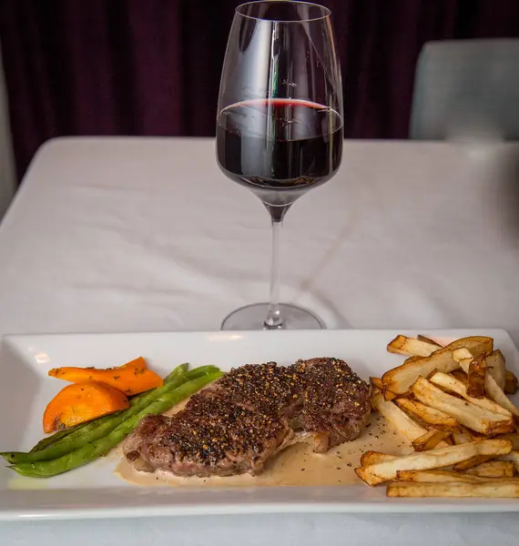 Steak and Wine Dinner with a side of vegetables and fries