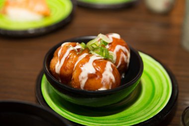 Japon Takoyaki aperatifi üzerine leziz sos ve yılan balığı sosu serpiştirilmiş.