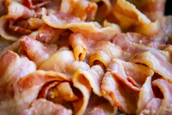 stock image Bacon sizzling in a pan on an outside grill