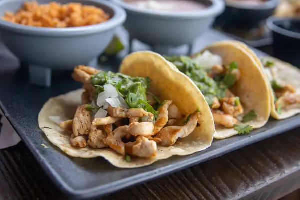 Mısır ekmeğine peynir dökülmemiş üçlü Tavuklu Taco.