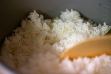 Buharda pişmiş beyaz pirinç ve ahşap bir kaşık.