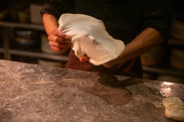 Şef yardımcısı roti canai ya da paratha hazırlıyor.