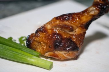 Soya sosu marine edilmiş tavuk bacağı kesme tahtasında.