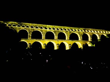 Fransa 'nın güneyinde yer alan Pont du Gard' ın gece fotoğrafı. Antik Roma su kemeri. Dünyanın her yerinden turistleri çeken görkemli ünlü bir köprü. Işıklarla aydınlatılan mimari işler.