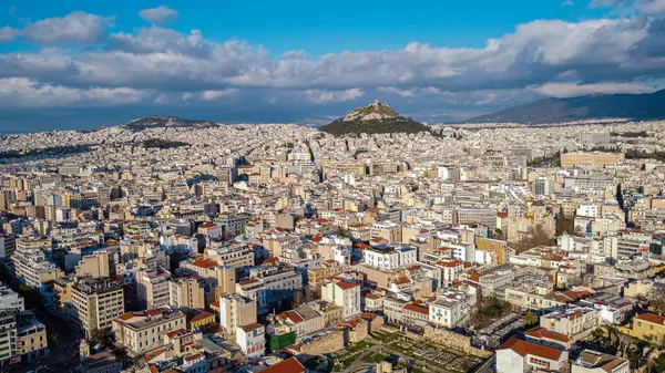 stock image Aerial view of the magnificent city of Athens, capital of Greece. Overpopulation of the metropolis that attracts tourists. High density of populations with clustered houses. Very busy tourist destination. Photo taken towards sunset over Athens.