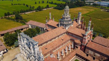 Certosa di Pavia seen from an aerial view, Italian wonders and art, historical monumental complex that includes a monastery and a sanctuary. green court and a church.The Ducale Palace on the right, Pavia, Italy. clipart