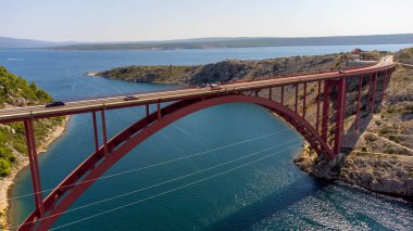 Doğal kıyı manzarasının ortasında ulaşım ve sürdürülebilirlik için inşaat. İki zıt parçayı birbirine bağlamak için deniz üzerindeki köprü. Maslenica Köprüsü, Hırvatistan.