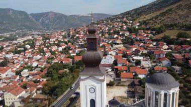 Bosna-Hersek 'in Mostar kentindeki Ortodoks Kutsal Üçlü Kilisesi. Şehir arkaplanlı kule etrafında hava yörüngesi.