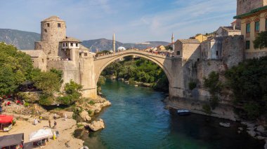 Ünlü Mostar Köprüsü 'nün üst manzarası. Yaz aylarında şehir arkaplanlı turist çekimini gösteren hava manzarası