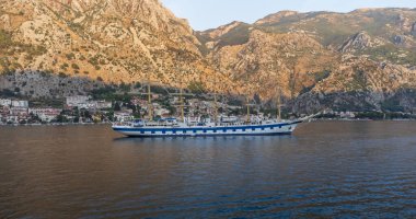 Akdeniz 'de, arka planda dağlarla birlikte Kotor Körfezi' ndeki görkemli yelkenli gemisinin sularının alçak açılı görüntüsü.