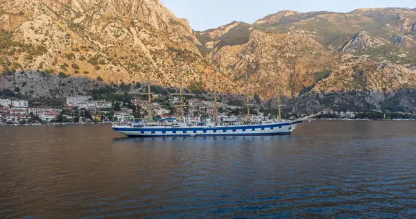 Akdeniz 'de, arka planda dağlarla birlikte Kotor Körfezi' ndeki görkemli yelkenli gemisinin sularının alçak açılı görüntüsü.