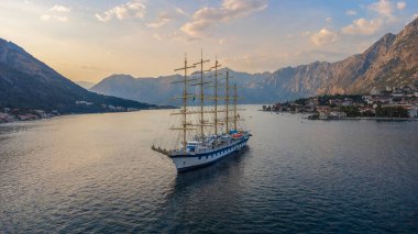 Royal Clipper yelkenli gemisinin gün batımı manzarası Kotor Körfezi 'nde, dağların arasında. Kullanılmış seyahat ve tatiller