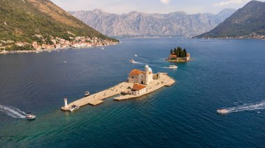 Arka planda Perast adlı turist kasabası bulunan Our Lady of the Rocks kilisesinin adaları. Perast kasabası ve Karadağ 'ın Kotor Körfezi kıyıları ile iki adanın hava manzarası