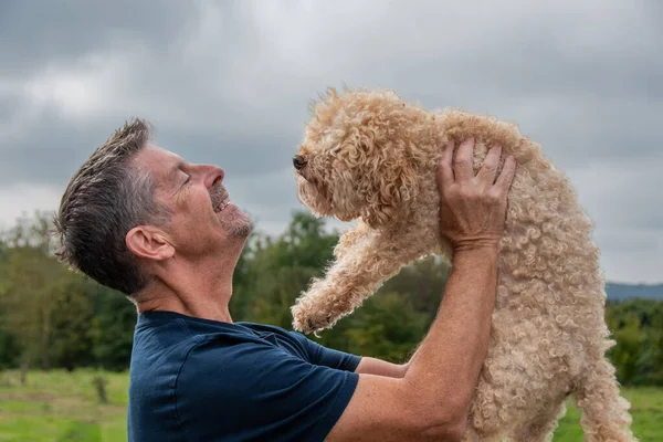 Man with his dog hugging and playing outdoor in the park. Toy poodle. Friendship and love concept. copy space.