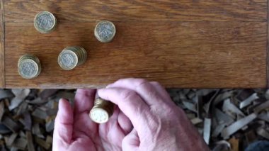Exeter İngiltere. 11-14-23. Finansal para imajı. Masadan bir insanın eline konan yarım kiloluk madeni paralar. İngiliz para birimi ve bankacılık veya tasarruf kavramı.  