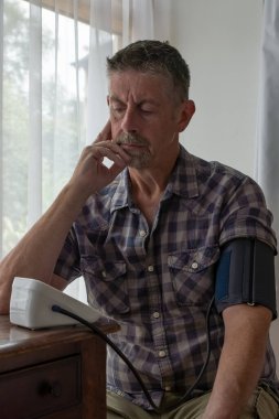 Kişisel bakım. Bir adam tansiyonunu ölçmek için makine kullanır. Düşük tansiyon değerlendirmesi. Kişisel bakım, sağlık.