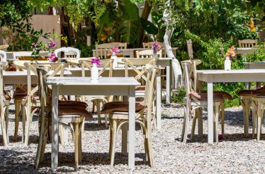 Greek restaurant tables under a vine canopy providing shady areas for people to sit. Alfresco dining cuisine. clipart