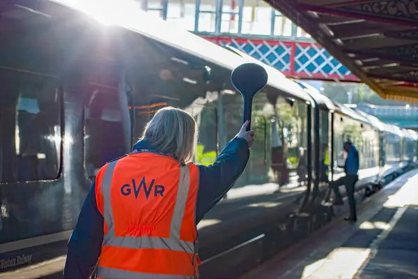 Torquay, Devon, uk. 2 Ocak 2023 Tren Kondüktörü, istasyondaki bir güvenlik görevlisine, trenin güvenli bir şekilde istasyondan ayrılmasına izin veren bir sinyal gönderiyor. Demiryolu işçileri sanayi harekatından önce görüntü aldılar