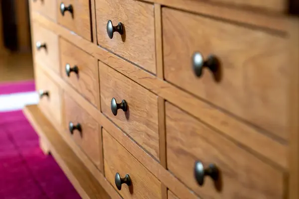 Cabinet of small drawers all closed. Wooden drawers with metal pull knobs. Selective focus on the second row of drawers. Storage in neat compartments in this piece of furniture. Home living  interiorsCabinet of small drawers all closed. Wooden drawer