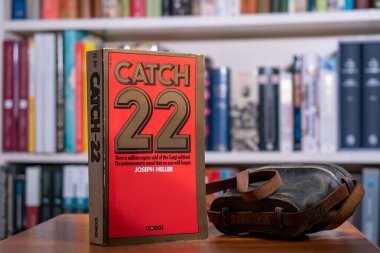 Churston, devon, uk. December 14th 2022. Catch 22 book by Joseph Heller. Selective focus on the centre of the front cover with a soft background of other books clipart