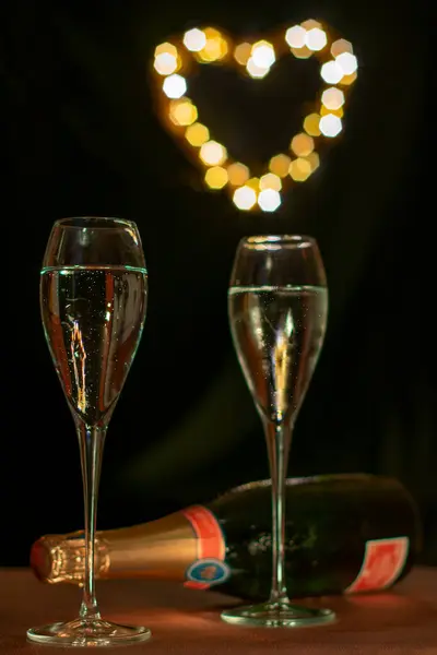 Romantic image with two glasses of frosted Champaign against a soft heart shaped light bokeh background. Selective focus on the left hand frosted glass.