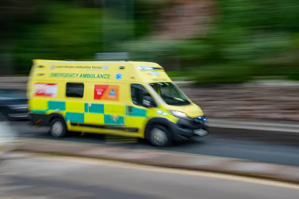 Torquay, Devom, uk. 09-18-23. Mavi ışıkları yanıp sönen, halka açık bir yol boyunca hareket bulanıklığı olan bir acil ambulans hızla ilerliyor. Sağlık görevlileri acil bir durumla ilgileniyorlar. Sarı ambulans.. 