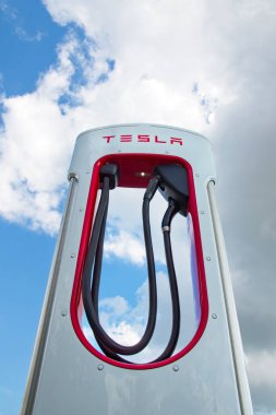 Exeter, Devon, İngiltere. 09-02-23. Tesla 'nın şarj noktası yerden yukarıya doğru eşsiz bir bakış açısıyla çekildi. Mavi ve bulutlu bir gökyüzü arka planına sahip bir Obelisk 'e benziyor. Uzayı kopyala Güçlü editoryal resim.
