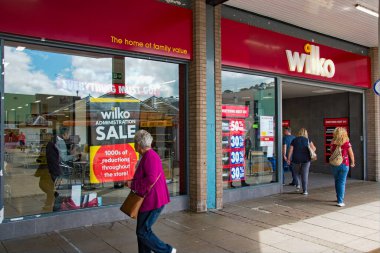 Newton Abbot, Devon, İngiltere. 08-21-23. Vitrininde satış posterleri olan bir Wilco mağazası. Dükkan kapanmakla tehdit edilirken müşteriler indirimleri kapıyor.. 